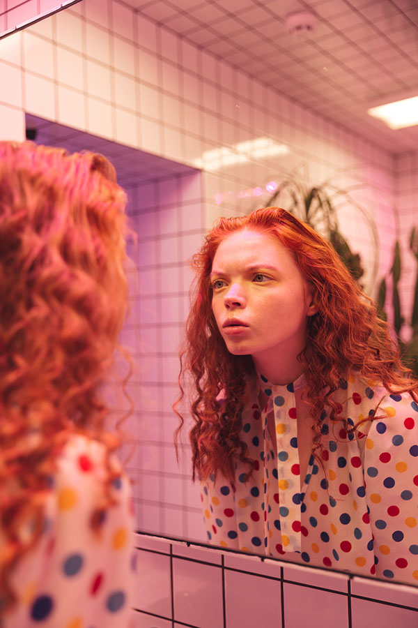 young redhead curly lady looking at mirror image